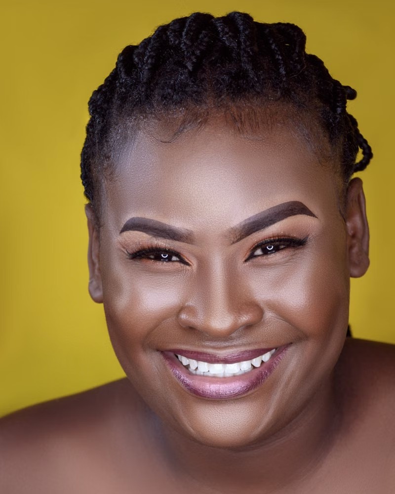 A smiling woman in a portrait against a yellow background
